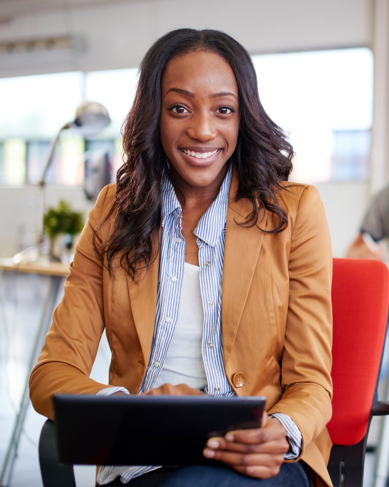Confident female designer working on a digital tablet in red creative office space